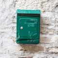 Old green mailbox attached to a stone wall.