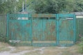 Old green metal gate and a closed iron door in brown rust on a wooden fence Royalty Free Stock Photo