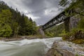 Old green railway bridge over wild river Enns in cloudy weather in Gesause National Park near town of Admont in centre Austria. Royalty Free Stock Photo