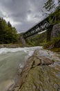 Old green railway bridge over wild river Enns in cloudy weather in Gesause National Park near town of Admont in centre Austria. Royalty Free Stock Photo