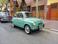 old green 1970s Fiat 600 sedan two door rear engined unibody parked in the street. Classic car show.