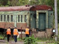 old green train car with orange roof and workers Royalty Free Stock Photo