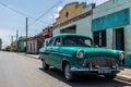 Old green vintage car parked before buildings in Cuba Royalty Free Stock Photo