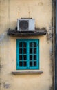 Old green window with air compressor on yellow wall