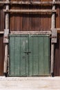 Old green wooden door made of plank on the wall Corrugated zinc fence with old rusty surface brown for the background Royalty Free Stock Photo