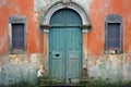 Old green wooden door on an orange wall in Venice, Italy