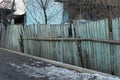 Old green wooden fence with broken boards on a rural winter street Royalty Free Stock Photo