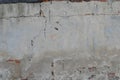 Old grey concrete garage wall with red bricks and cracks