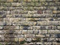 Old grey damp stone wall made of large regular blocks covered in patches of moss Royalty Free Stock Photo