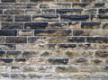 Old grey damp stone wall made of large regular blocks covered in patches of moss