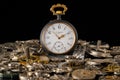 Old grey pocket watch with golden hands on pile of gears. Gearwheels, cogwheels and metal bracelet on black background