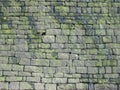 Old grey stone wall made of large irregular blocks covered in patches of moss