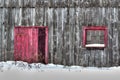 Close up of old gray wood planks barn in a snow field with red door and red window Royalty Free Stock Photo