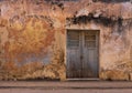 Old grunge cracked concrete wall with some stains and holes. White brown and orange collors. with old door Royalty Free Stock Photo