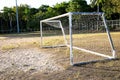 Old grunge football goal on dry grass field in soccer stadium