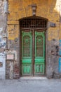 Old grunge green decorated painted door on dirty yellow painted stone wall