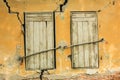 Old grunge retro pair window with wooden shutters at yellow cracked wall