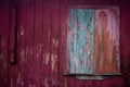 Old grunge and weathered home facade with green window and red wall planks texture background