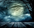 Old grunge wooden table in front of scary night scene. Halloween composition background with scary dark forest and evil moon. Royalty Free Stock Photo
