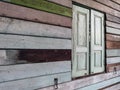 Old grunged wooden window frame painted white vintage with old colourful plywood wall. Antique window frame and old panes. Old Royalty Free Stock Photo