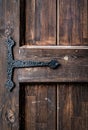 An old grungy, brown, natural wooden door part with grains and with black metal hinge, for background and texture. Royalty Free Stock Photo