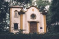 Old and grungy church with closed wooden doors, surrounded by tall trees Royalty Free Stock Photo