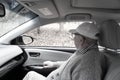 Elderly man looks out at autumnal fallen leaves from car