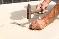 Old hammer and nail in the hands of an elder man. Carpenter hammers a nail into a tree. Old hammer and nail in the hands of an Royalty Free Stock Photo