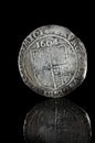 Old, hammered silver coin exposed on black reflecting glass, found in life dig by metal detector.England.