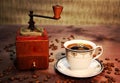 An old hand grinder andÃ¢â¬â¹ a cup of coffee on a wooden background. Royalty Free Stock Photo