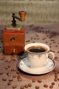An old hand grinder andÃ¢â¬â¹ a cup of coffee on a wooden background. Royalty Free Stock Photo