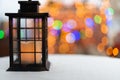 Old hand lantern with barely smoldering candle inside. On the second burn the background is blurred with Christmas tree Royalty Free Stock Photo