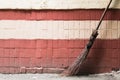 Old hand made street's broom against a brick wall