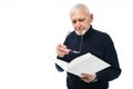 Old handsome man with gray hair and beard in sweater thoughtfully reading book holding eyeglasses in hand over white Royalty Free Stock Photo