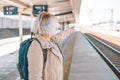 Old happy woman with backpack waiting train on station platform with backpack, passport and ticket shows the direction Royalty Free Stock Photo