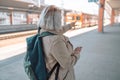 Old happy woman with backpack waiting train on station platform with backpack, passport and ticket shows the direction Royalty Free Stock Photo