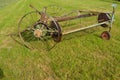 Old hay tedder machine on a field