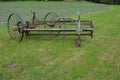 Old hay tedder machine on a meadow