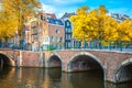 Old heart of Amsterdam. Beautiful autumn, golden falling leaves, old sloping houses, bridges and canals. Autumn day in Amsterdam. Royalty Free Stock Photo