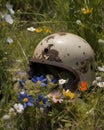 An old helmet and fatigues buried in the midst of an array of wildflowers Abandoned landscape. AI generation