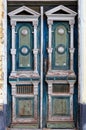 Old weathered wooden entrance doors with carved elements and a symmetrical pattern at the entrance of an old house