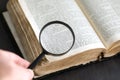 Old historic paper text book opened and magnifying glass in hand. Bible, dictionary, antique document research with loupe. Royalty Free Stock Photo