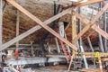 Old historic ship being restored - image from below hull with lumber used to hold and prop up vessel and man on ladder looking Royalty Free Stock Photo