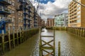 Old historic warehouse now converted into housing bordering the River Thames with green mud and moss from low tide in the Royalty Free Stock Photo