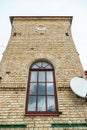 An old historical building made of red brick and vintage arched windows on the walls. A modern satellite dish on the wall of a Royalty Free Stock Photo