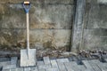 an old hoe leaning against a wall, placed on a paving block