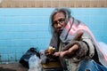 An old homeless Asian man is reaching out to a passerby asking for money for food because he has no job and no home and has to Royalty Free Stock Photo