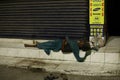 Chennai, India-May 01 2020: Old Homeless Indian woman laying on the street in front of shop shutters. India