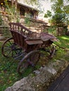 Old horse cart made of brown wood and rusty iron. Traditional moldovan rural transport. Wooden fence and wall of stone background Royalty Free Stock Photo