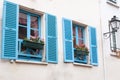 Old house beige wall with two windows with opened blue wooden shutters and decorative flowers Royalty Free Stock Photo